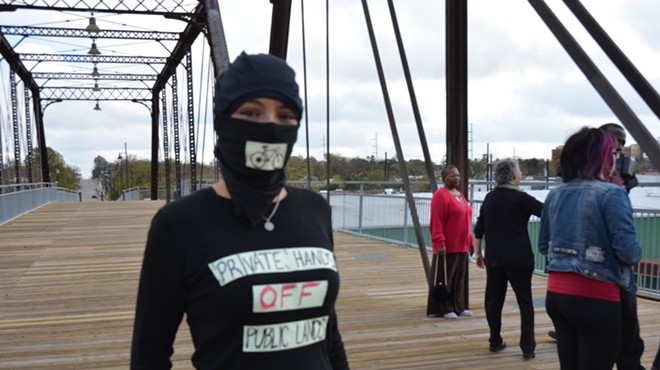 A protester stands on the Hays Street Bridge during the Alamo City Beer ribbon cutting ceremony on Friday, December 5.