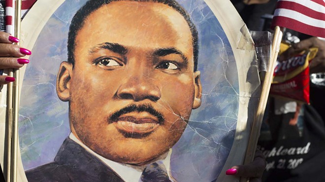 A participant in the 2014 MLK Day March in San Antonio holds up an image of Dr. Martin Luther King, Jr.