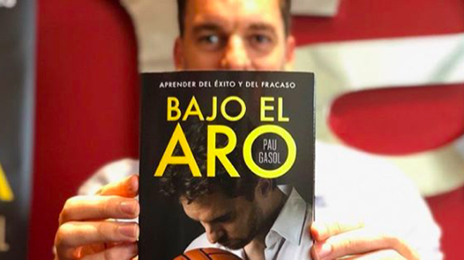 Pau Gasol shows off a copy of his autobiography, Bajo El Aro.