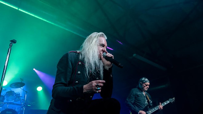 Saxon singer Biff Byford leans on the monitor while guitarist Paul Quinn unleashes a monster riff.