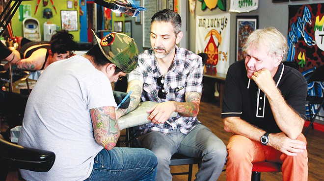 Steve Candelario of Mr. Luckys Tattoo does a tune up on Ricky Armendariz's arm as Gary Sweeney looks on.
