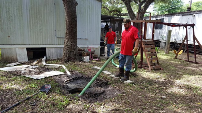 Maintenance staff clean up raw sewage outside an Oak Hollow home.