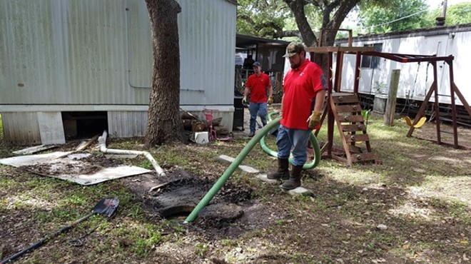 Maintenance staff clean up raw sewage outside an Oak Hollow home in October 2016.