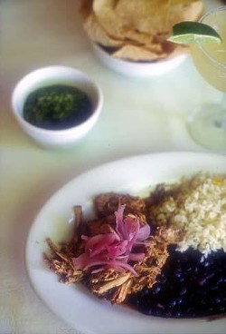 A plate of Cochinita Pibil with rice and beans, and the astounding green salsa nearby.