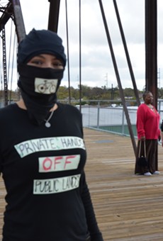 A protester stands on the Hays Street Bridge during the Alamo City Beer ribbon cutting ceremony on Friday, December 5.