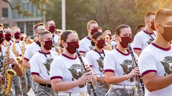 Members of the Aggie Band march through the Texas A&M campus while wearing masks.