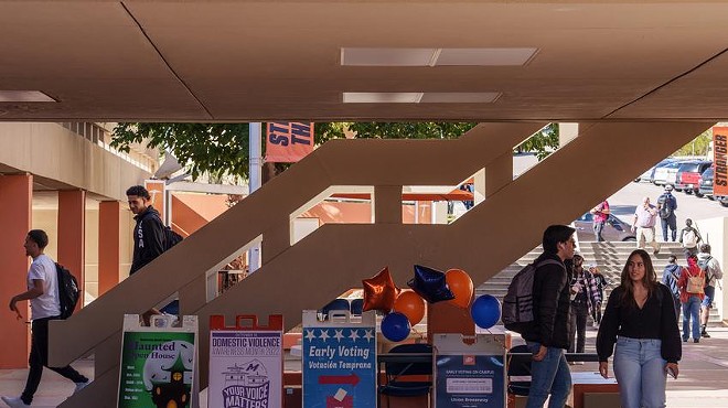 Students walk past signs promoting early voting at the University of Texas at El Paso on Tuesday.
