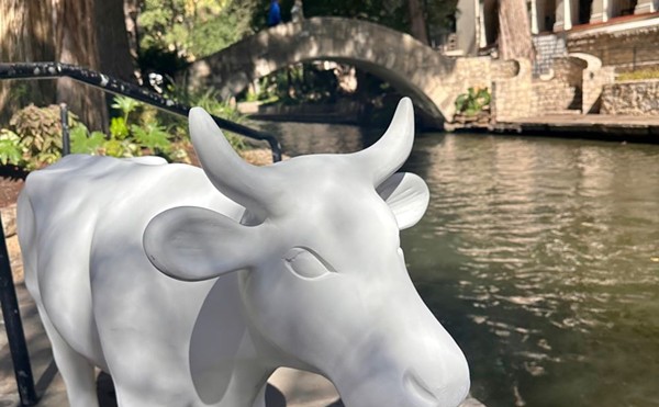 An unpainted CowParade sculpture stands on the San Antonio River Walk.