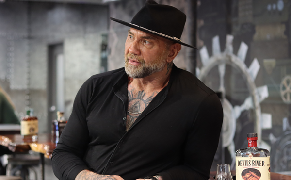 Actor Dave Bautista (left) stands next to a glass of Devils River Whiskey.
