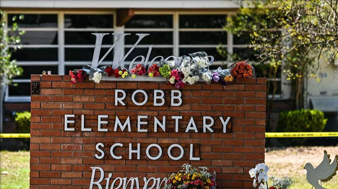Flowers decorate the sign in front of Robb Elementary school after a shooting there took the lives of 19 children and two teachers.
