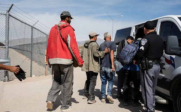 A group of migrants walk to an El Paso County Sheriff transport van to be taken to processing on March 20, 2024. State troopers have responded to efforts by migrants to rush through border gates en masse by charging hundreds of migrants with rioting.