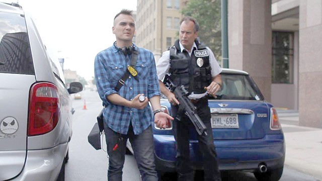 Filmmaker Mark Cantu (left) demonstrates the correct way to unload an assault rifle to actor James Allen Chapman in downtown SA - COURTESY PHOTO