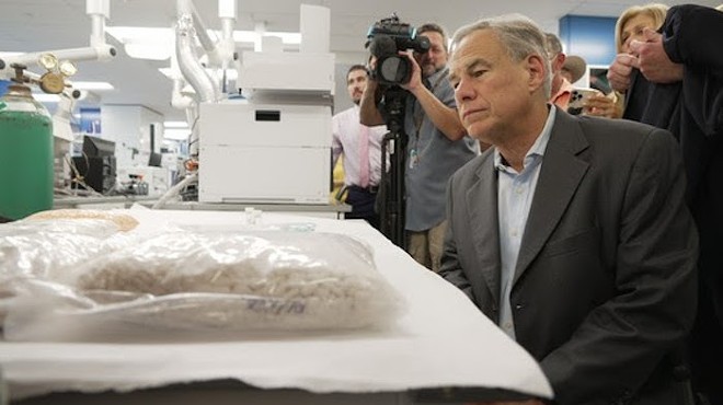 Gov. Greg Abbott looks at a bag of fentanyl during a photo op earlier this year.