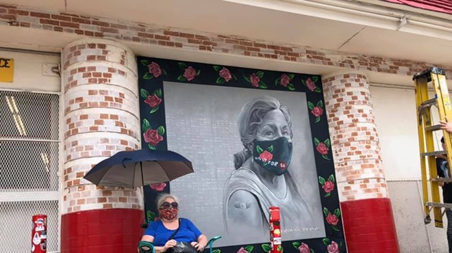 San Antonio based artist Kim Bishop's mother sits next to her daughter's mural outside of Jefferson Bodega.