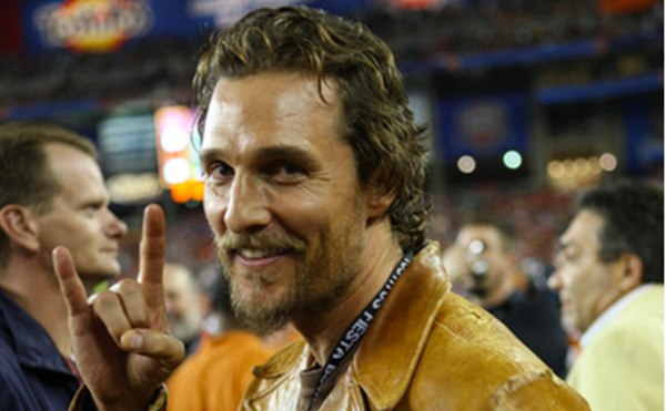 Matthew McConaughey flashes the hook 'em horns sign at a UT football game.