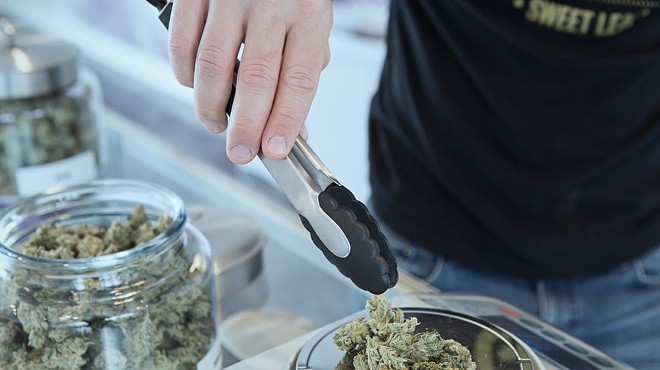 A person at a dispensary weighs cannabis flower. Needless to say, this photo wasn't taken in Texas.
