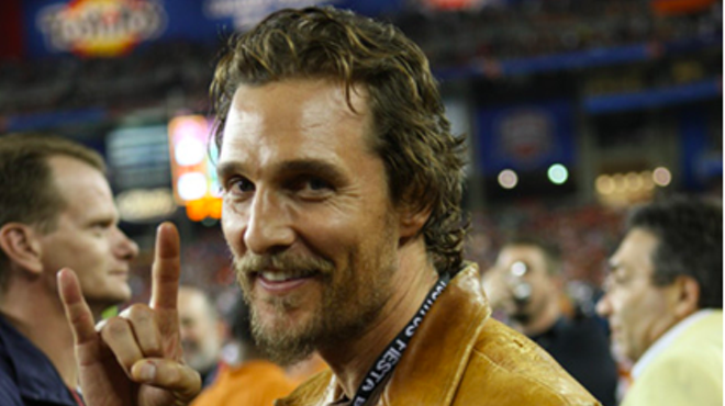 Matthew McConaughey flashes the hook 'em horns sign at a UT football game.