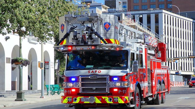 A San Antonio fire truck travels a city street with its emergency lights on.