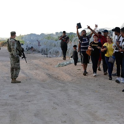 A group of migrants seeking U.S. asylum crawl through razor wire on the banks of the Rio Grande River to enter the U.S. and turn themselves in to authorities.