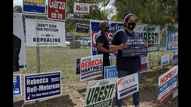 Opponents of Fix SAPD's petition drive hold up signs at a polling site where volunteers collected signatures last fall.