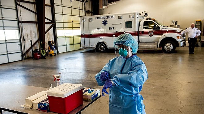A medic pulls on gloves as she gets ready to work at a mobile testing site in the Texas Hill Country.