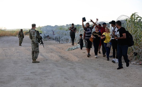 A group of migrants seeking U.S. asylum crawl turn themselves in to authorities after crawling through razor wire on the banks of the Rio Grande.