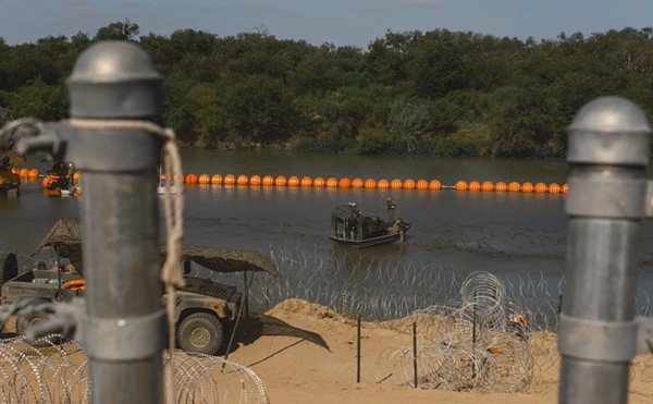 State law enforcement officers stand guard as workers construct a string of buoys being deployed to prevent migrants from swimming across the Rio Grande in Eagle Pass on July 14, 2023.