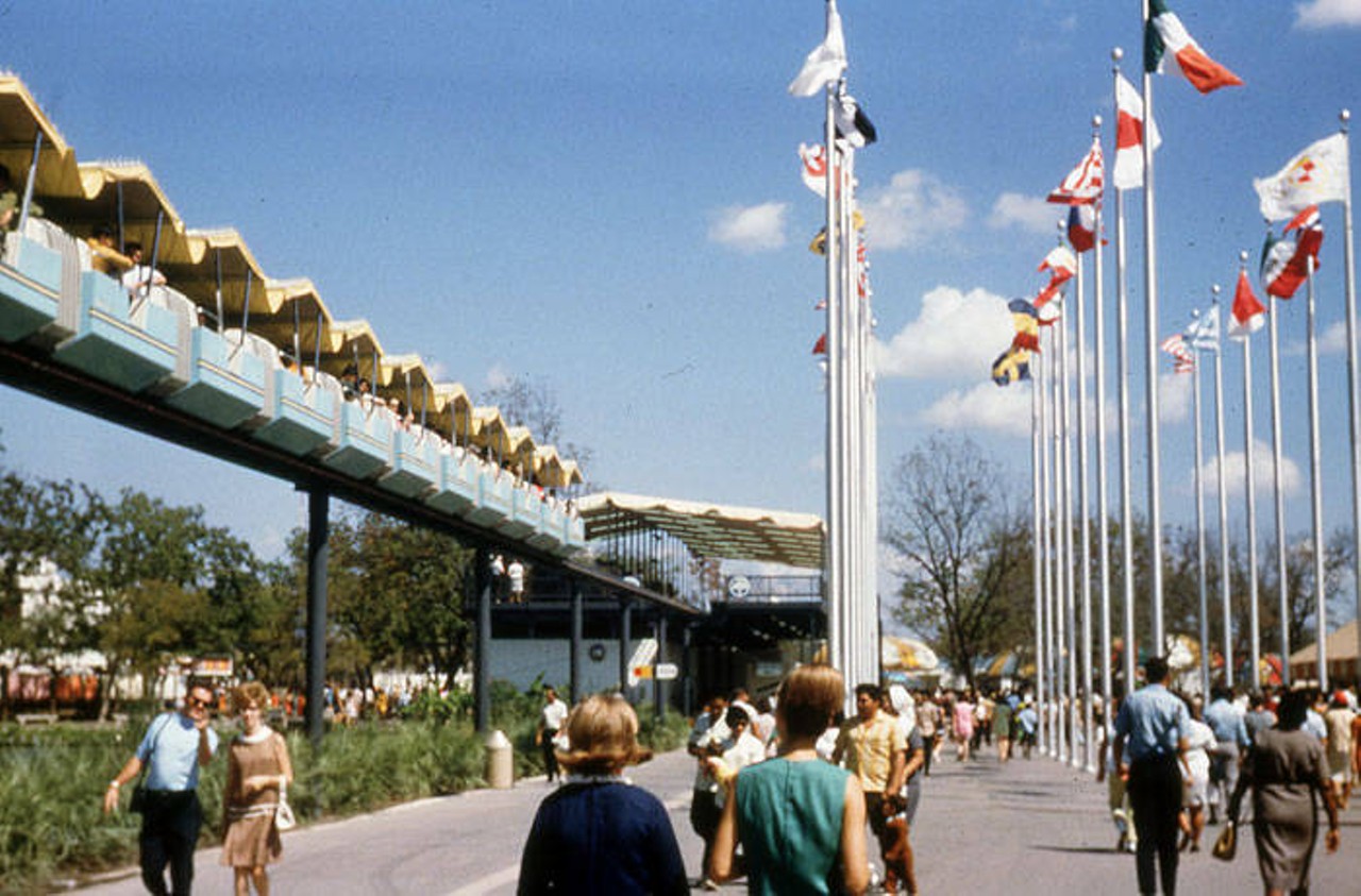 Mini-monorail passes the flags outside the Institute of Texan Cultures (Texas Pavilion)