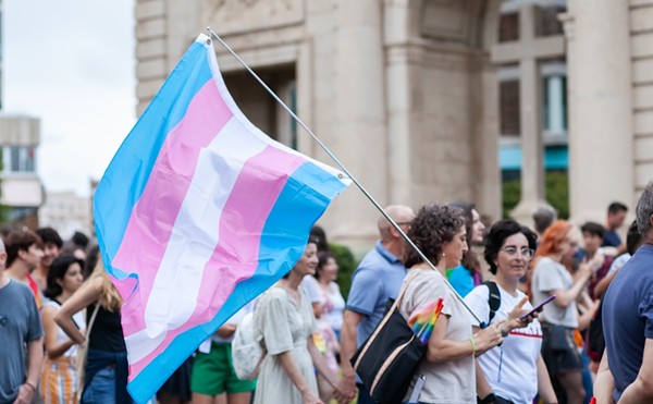 A marcher carries a flag representing transgender rights during a protest.