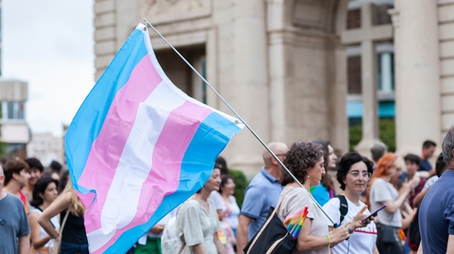 A marcher carries a flag representing transgender rights during a protest.