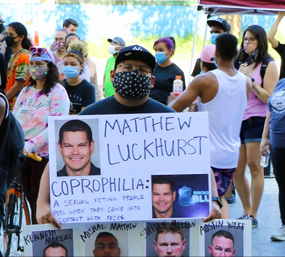 A protester at a recent San Antonio anti-police brutality demonstration holds up a sign showing fired officer Matthew Luckhurst's photograph. - JAMES DOBBINS