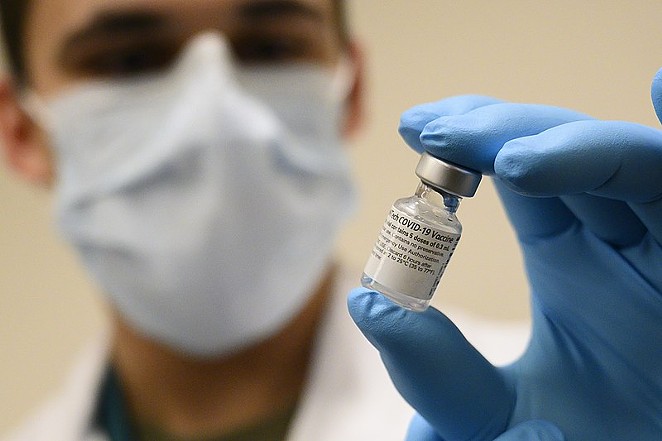 A medical professional holds a vial of the COVID-19 vaccine. - U.S. SECRETARY OF DEFENSE