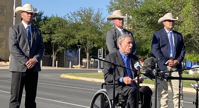 Ranger Dick: Gov. Greg Abbott reads from a speech in front of Freeman Coliseum as members of the Texas Rangers stand behind him. - SANFORD NOWLIN