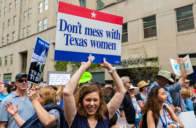 A protester carries a sign defending women's reproductive rights. - Shutterstock