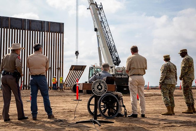 Gov. Greg Abbott watched a crane lifting a section of the border wall in place near the Rio Grande after he unveiled the new wall during a press conference last week. - TEXAS TRIBUNE / JASON GARZA