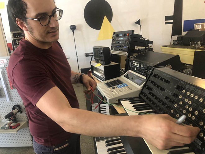 Luis Faraklas Trevino shows off a vintage synthesizer on the floor of Output Audio, which also includes a recording studio. - BILL BAIRD