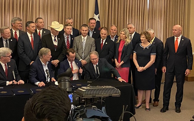 Their master's voice: Gov. Greg Abbott listens intently as NRA chief Wayne LaPierre speaks during a 2021 ceremony where the governor signed seven bills easing firearms regulations. - SANFORD NOWLIN