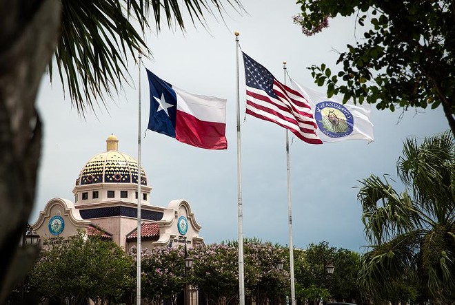 The city, state and national flags fly over city hall in Rio Grande City on June 17, 2021. Starr County, of which Rio Grande City is the seat, has more 100-degree days than any other county in Texas, according to a new study. - Texas Tribune / Jason Garza