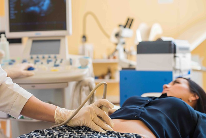 A woman receives ultrasound in a clinic. - Shutterstock / Reshetnikov_art