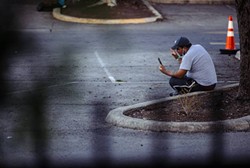 A migrant sits on a curb at the resource center in San Antonio. - Texas Tribune / Chris Stokes