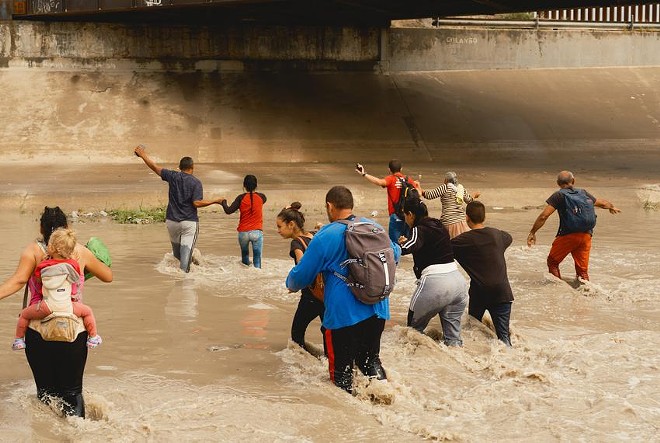 A group of migrants from Venezuela crosses the Rio Grande toward a temporary border patrol processing facility on Oct. 6 in El Paso. - Texas Tribune / Jordan Vonderhaar