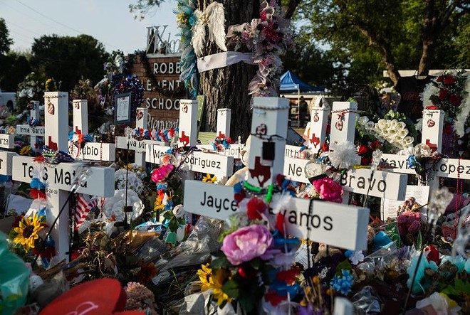 Hundreds of flowers, toys and candles surround a memorial in June for the 21 victims killed in the Robb Elementary shooting in Uvalde. - Texas Tribune / Evan L'Roy