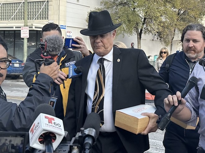 Clayton Perry walks to city council offices last fall as reporters ask him about his legal woes. - Michael Karlis