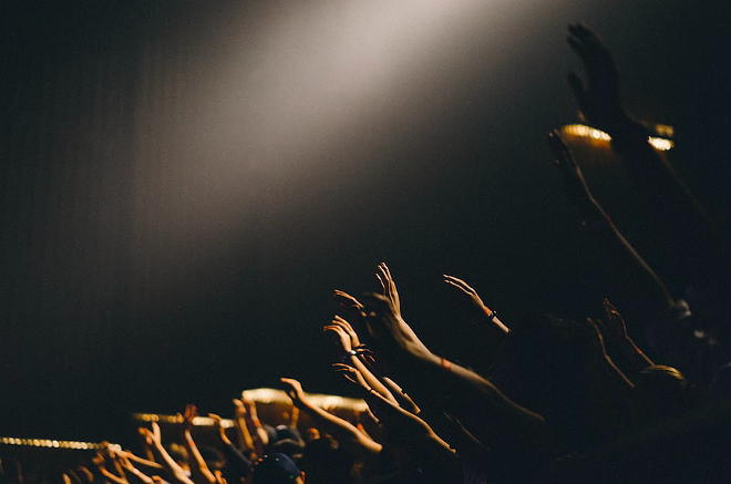 Members of a church congregation raise their arms to the sky. - Unsplash / Edwin Andrade