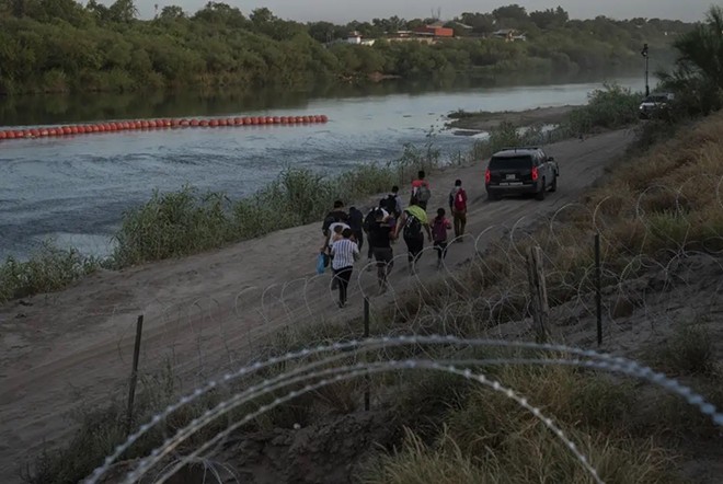 Migrants follow a Texas Department of Public Safety vehicle after turning themselves in. They crossed through a gap in the concertina wire on the Urbinas’ property. - Texas Tribune / Verónica G. Cárdenas