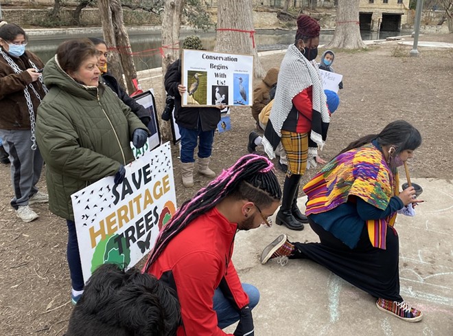 District 2 City Councilman Jalen McKee-Rodriguez kneels as Native American activists conduct a ceremony during a protest against San Antonio's effort to cut down trees inside Brackenridge Park. - Sanford Nowlin