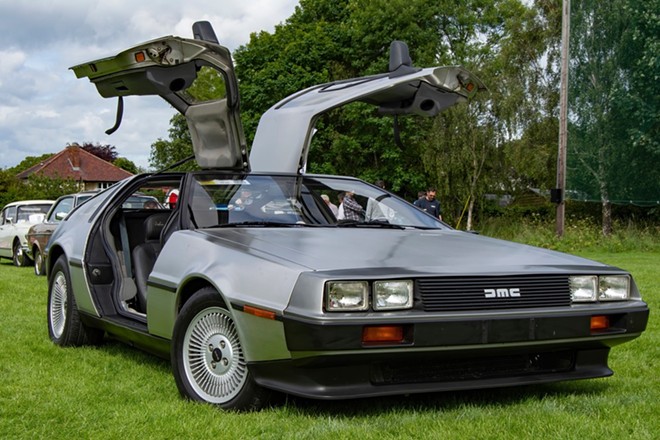 An original 1980s-era DeLorean on display with its gull-wing doors open. - Shutterstock / Ross Mahon