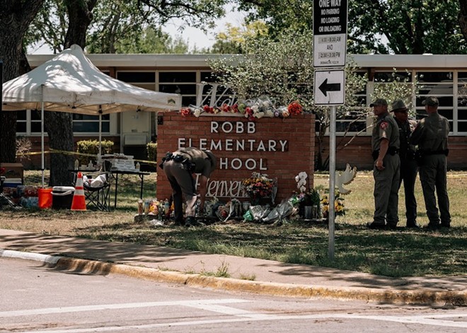 Members of law enforcement lay flowers at a makeshift memorial outside Robb Elementary School shortly after the shooting. - Joseph Guillen