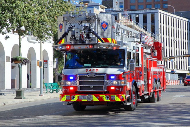A San Antonio fire truck travels a city street with its emergency lights on. - Shutterstock / JustPixs