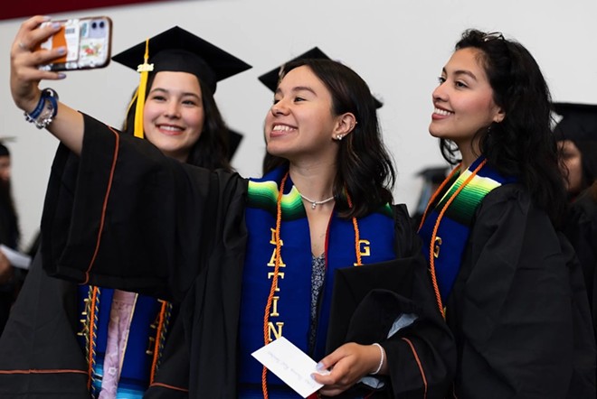 Graduates take a selfie prior to the University of Texas at Austin Latinx Graduation on May 9, 2024 in Austin. The graduates received orange chords, a nod to the color of monarch butterflies that symbolize the resilience of Latinx immigrants. Credit: Maria Crane/The Texas Tribune - Texas Tribune / Maria Crane